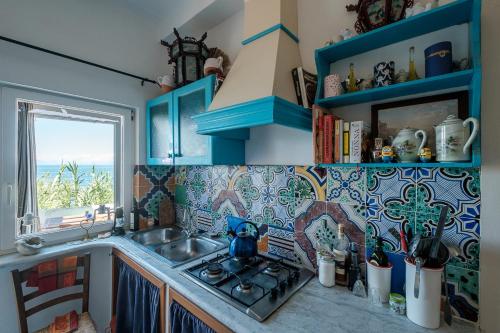 eine Küche mit blauen Schränken, einem Waschbecken und einem Fenster in der Unterkunft La rosa dei venti in Procida