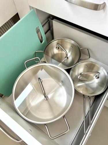 three metal pans sitting on top of a kitchen counter at Apartament Aviator in Mielec