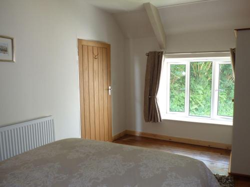 um quarto com uma cama e uma grande janela em Spring Garden Cottage em Carmarthen
