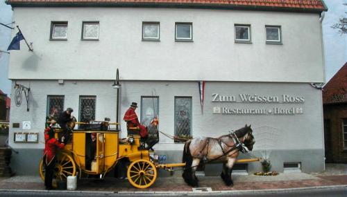 a horse pulling a yellow carriage in front of a building at Restaurant und Hotel Zum Weissen Ross in Mölln