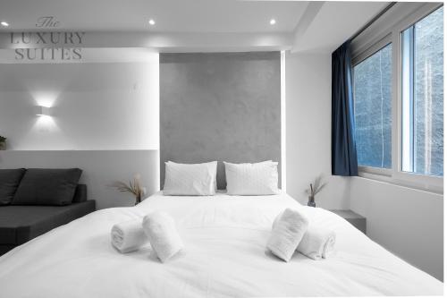 a white bedroom with a large white bed with pillows at Adelle Apartments, The Luxury Suites in Thessaloniki