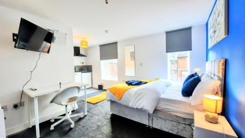 a bedroom with a bed and a desk and a tv at Burford Road - Stay. Sleep. Rest. in Nottingham