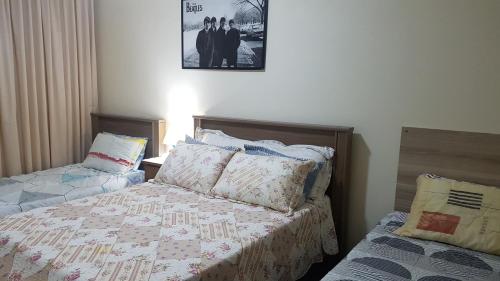 ein Schlafzimmer mit zwei Betten und einem Bild an der Wand in der Unterkunft Apartamento Familiar Com ou Sem Ar Condicionado in Porto Alegre