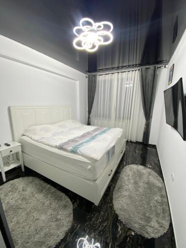 1 dormitorio con 1 cama blanca y 2 alfombras en Apartament 105 - HF Building Resort, en Mamaia Nord – Năvodari