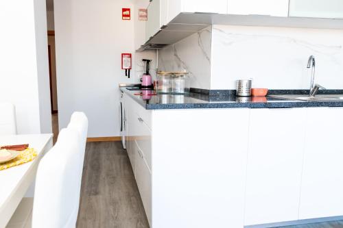 a kitchen with white cabinets and a sink at O Cardanho dos Galfarritos - A Casa dos Miúdos in Aveiro