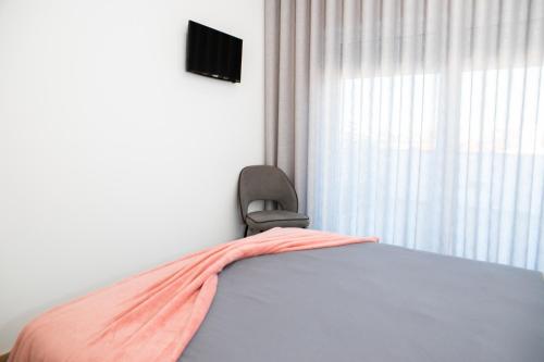 a bedroom with a bed and a chair and a window at O Cardanho dos Galfarritos - A Casa dos Miúdos in Aveiro