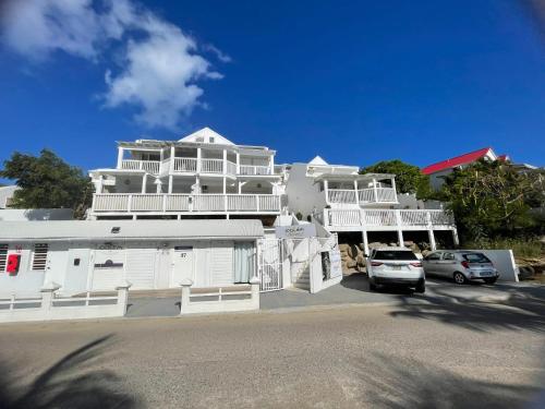 un gran edificio blanco con coches estacionados frente a él en Petit coin de paradis à 5 min Baie Orientale, Idolem résidence unité 7bis - 57 Rue du Mont Vernon 1, en Cul de Sac