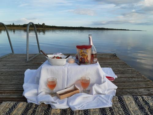 a table with a bottle of wine and glasses on a dock at Päikesemajake 2 in Soonlepa