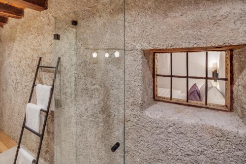 a glass shower in a stone bathroom with a window at Boutiquehotel Rattenberg in Rattenberg