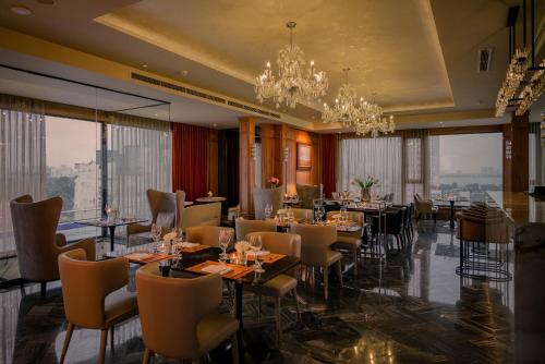 a restaurant with tables and chairs and a chandelier at Le Jardin Hotel Haute Couture in Hanoi