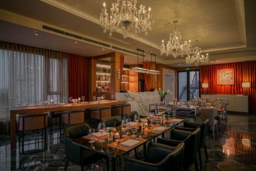 Le Jardin Hotel Haute Couture في هانوي: غرفة طعام بها طاولات وكراسي وثريات