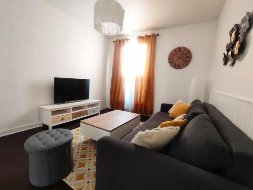 a living room with a couch and a tv at Appartement proche Paris/Métro in Asnières-sur-Seine