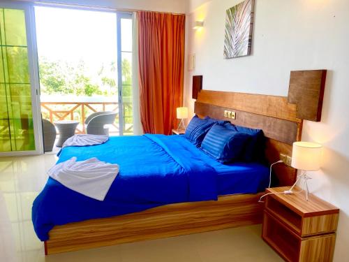 1 dormitorio con cama azul y balcón en Sands Grand Hotel, en Dhigurah