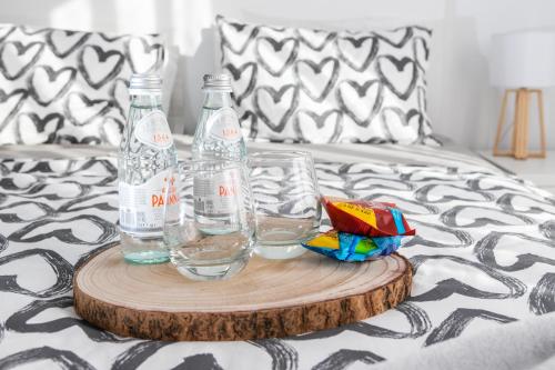 a tray with two bottles and glasses on a bed at O Cardanho dos Galfarritos - A Casa dos Miúdos in Aveiro