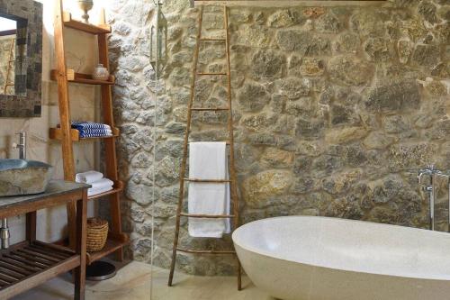 a bathroom with a bath tub and a stone wall at Kasbah 1 in Cala Vadella