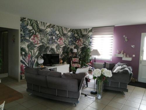 una sala de estar con 2 sofás y una pared de flores en La conviviale, en Saintes