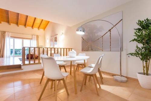 a dining room with a white table and white chairs at Villas T3 com Jardim Vila Sagres in Sagres