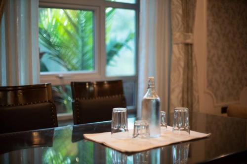 a table with glasses and a bottle on top of it at Stay Leisurely Clair De Lune 2BHK pvt jacuzzi, Alibaug in Alibaug