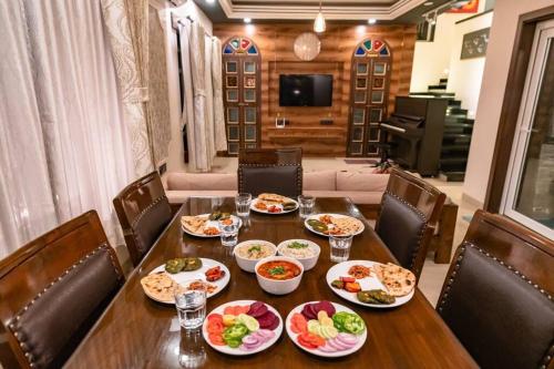 a wooden table with plates of food on it at Stay Leisurely Clair De Lune 2BHK pvt jacuzzi, Alibaug in Alibaug
