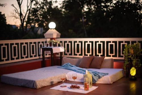 a bed on a patio with two glasses of wine at Stay Leisurely Clair De Lune 2BHK pvt jacuzzi, Alibaug in Alibaug