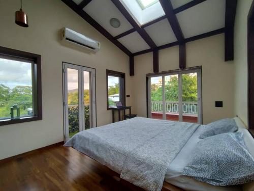 a bedroom with a large bed and two windows at Stay Leisurely Clair De Lune 2BHK pvt jacuzzi, Alibaug in Alibaug