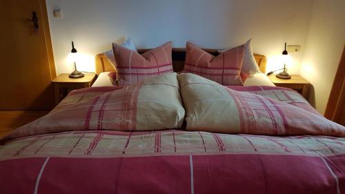 a large bed with pink and gray blankets and pillows at Ferienwohnung Moosegger in Bad Feilnbach