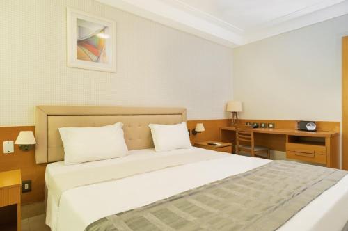 a hotel room with a bed and a desk at Royal Macaé Palace Hotel in Macaé