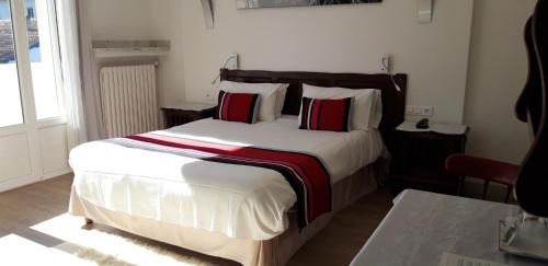a bedroom with a large bed with red and white pillows at Hotel Uhainak in Hendaye