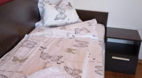 a bed with a butterfly blanket and a night stand at HOTEL DECENTRIA in Timişoara