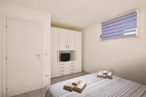 um quarto branco com 2 camas e uma televisão em Corallo House Alghero em Alghero