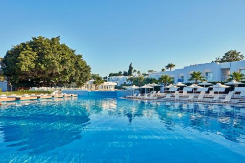 uma grande piscina com cadeiras e guarda-sóis em So Nice Club Resort em Agia Napa