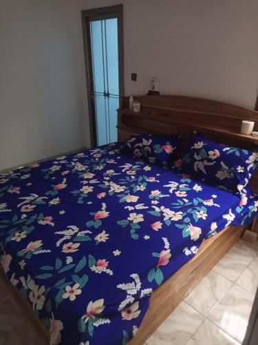 a bed with a blue comforter with flowers on it at Reserva africa Cité Mokpokpo in Lomé