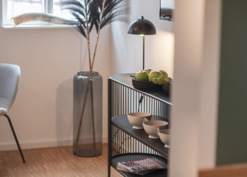 a black shelf with bowls and a vase with a plant at St. Salvator Apartments in Fulda