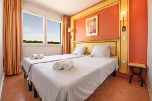 two beds in a hotel room with towels on them at SOWELL Family Grau du Roi in Le Grau-du-Roi