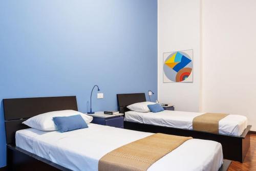 two beds in a room with blue walls at Piola Flexyrent apt. A.C. WiFi in Milan
