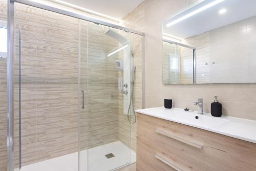 een badkamer met een glazen douche en een wastafel bij Ohana Townhouse in Arona