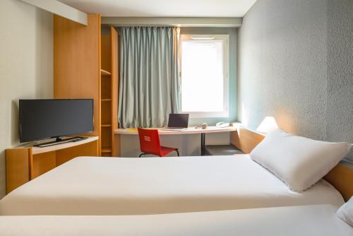 a hotel room with a bed and a desk and a television at ibis Saint Rambert d'Albon in Saint-Rambert-dʼAlbon