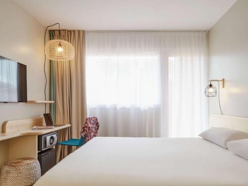 - une chambre avec un grand lit blanc et une fenêtre dans l'établissement ibis Thalassa Hyeres Plage, à Hyères