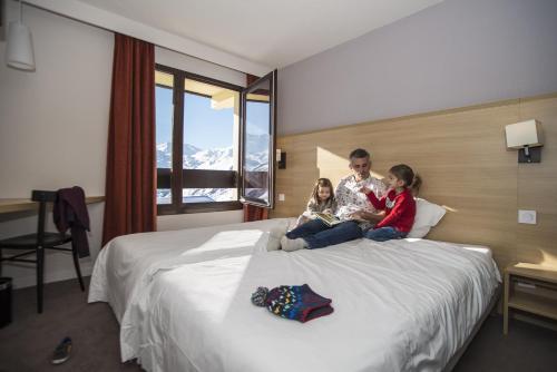 a man and two children sitting on a bed at Villages Clubs du Soleil - LES MENUIRES in Les Menuires