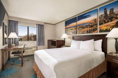 a hotel room with a bed and a desk at Baymont by Wyndham Monterey Park in Monterey Park