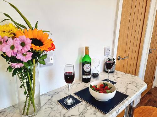 een tafel met een vaas met bloemen en een fles wijn bij Modern Apt near Train Station and Ideal for Long Stays in Leicester