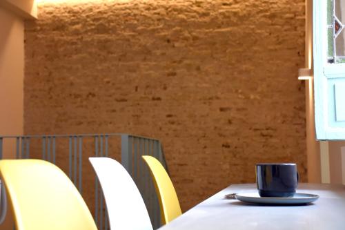 a coffee cup sitting on a table with yellow chairs at Alegoría Coliving Experience Residencia in Seville