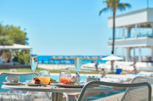 a table with a plate of food and wine glasses at So Nice Beach Resort in Ayia Napa