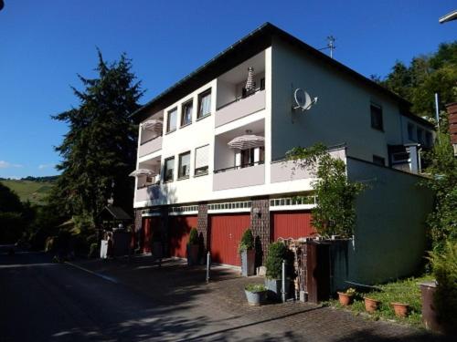 um edifício branco com uma garagem vermelha ao lado de uma rua em Apartment Der Malerwinkel-3 by Interhome em Enkirch