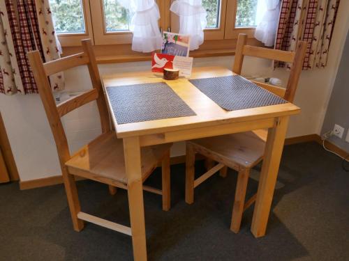 Apartment Schwendihus by Interhome في جريندلفالد: طاولة خشبية مع كرسيين وطاولة وكرسي