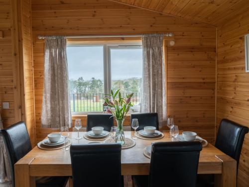 ein Esszimmer mit einem Tisch, Stühlen und einem Fenster in der Unterkunft Chalet Loch Leven Lodge 6 by Interhome in Kinross