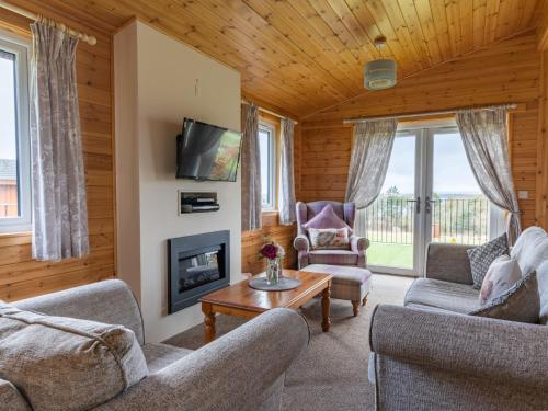 a living room with two couches and a fireplace at Chalet Loch Leven Lodge 6 by Interhome in Kinross