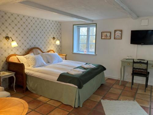 a bedroom with a bed with a television and a table at Lunkaberg Bed & Breakfast in Simrishamn
