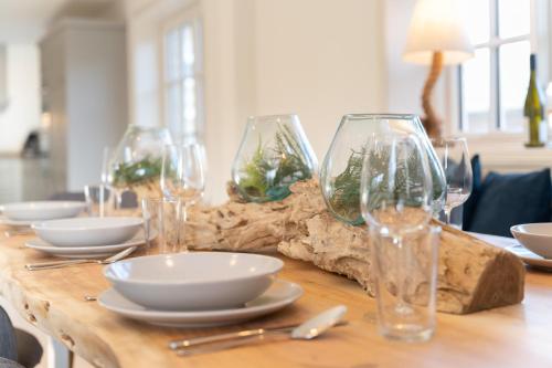 a wooden table with wine glasses and plates on it at Landhaus Marie in Oldsum