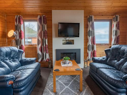 uma sala de estar com sofás, uma televisão e uma mesa em Chalet Loch Leven Lodge 12 by Interhome em Kinross